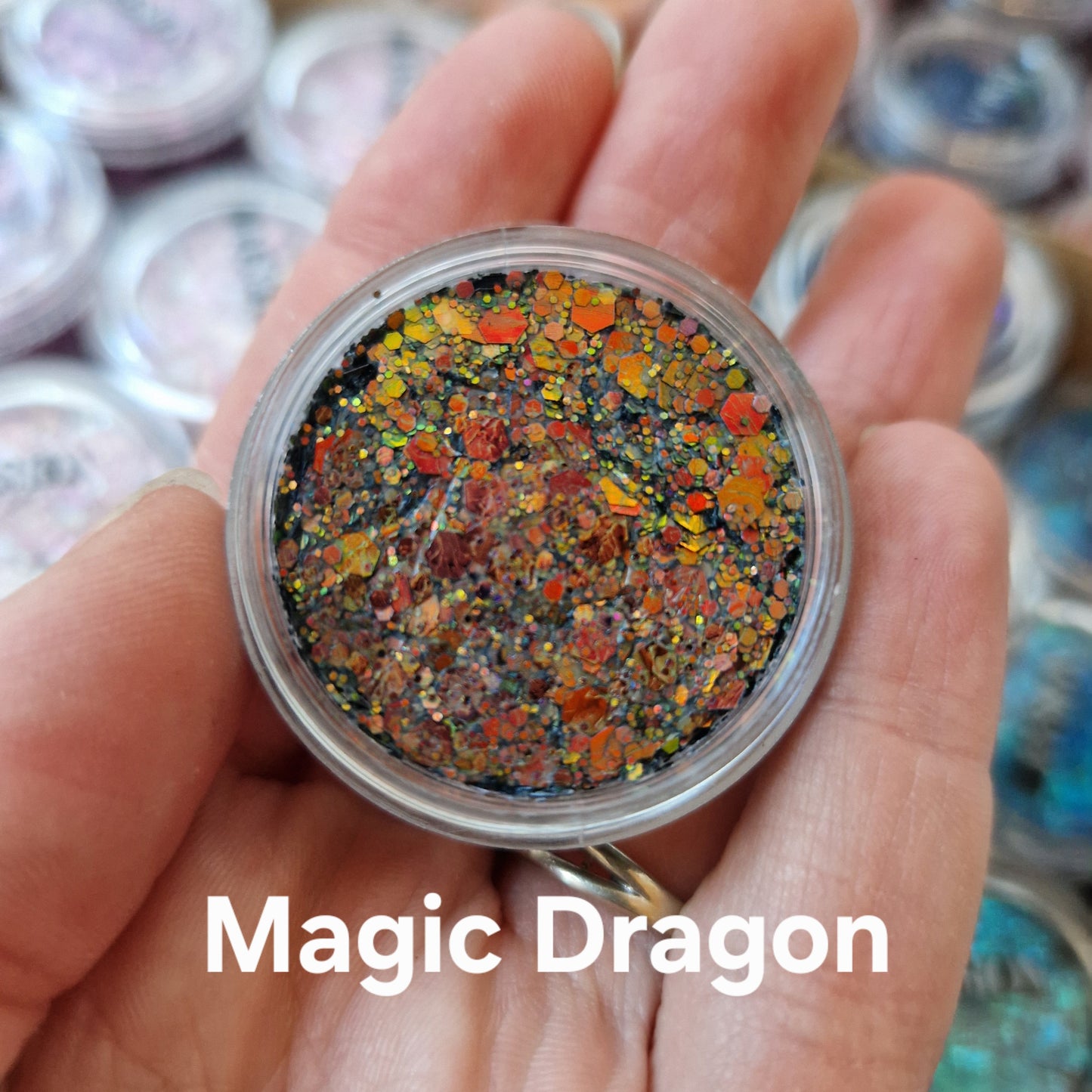 Magic Dragon glitter cream i hånd - rød, orange og gul glitter på sort base til makeup og ansigtsmaleri