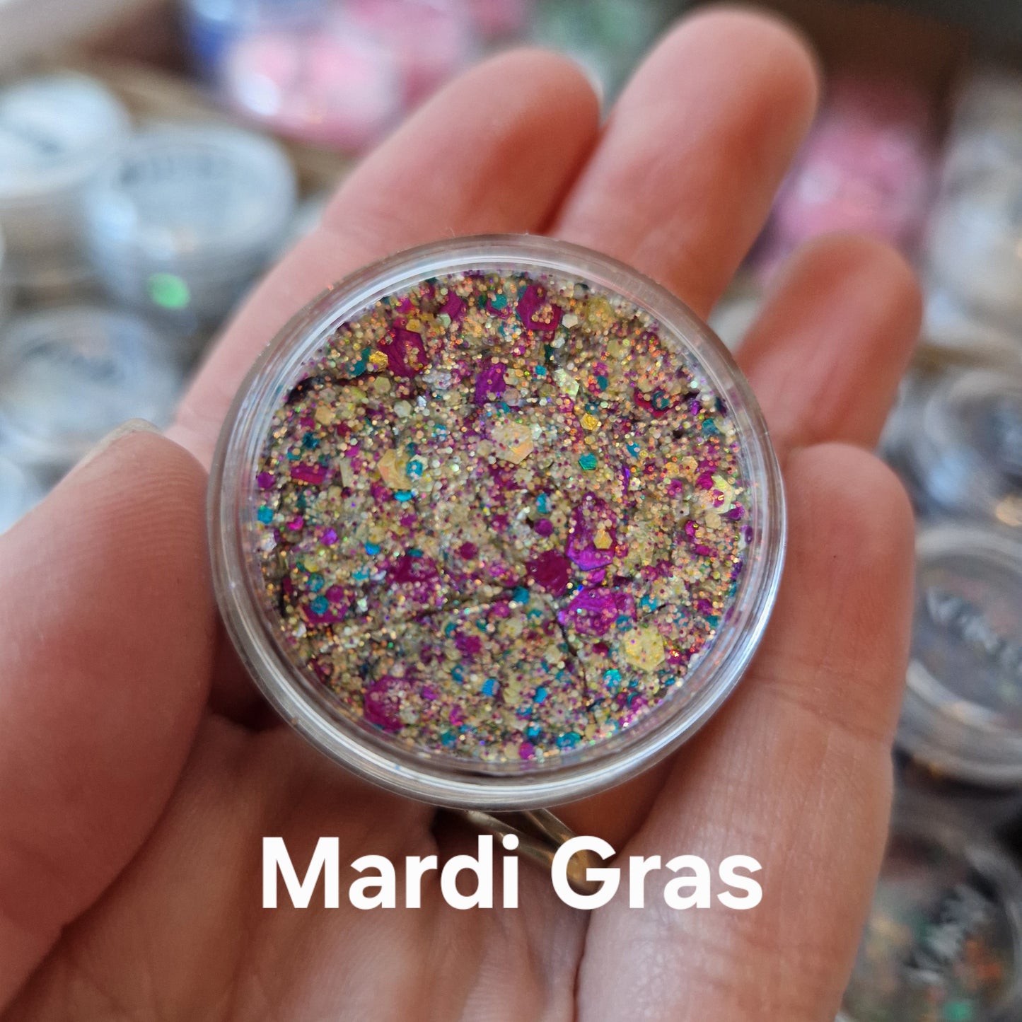 Mardi Gras Glitter Cream i hånd – farverig glitter med lilla, guld og turkis shimmer til makeup og bodyart