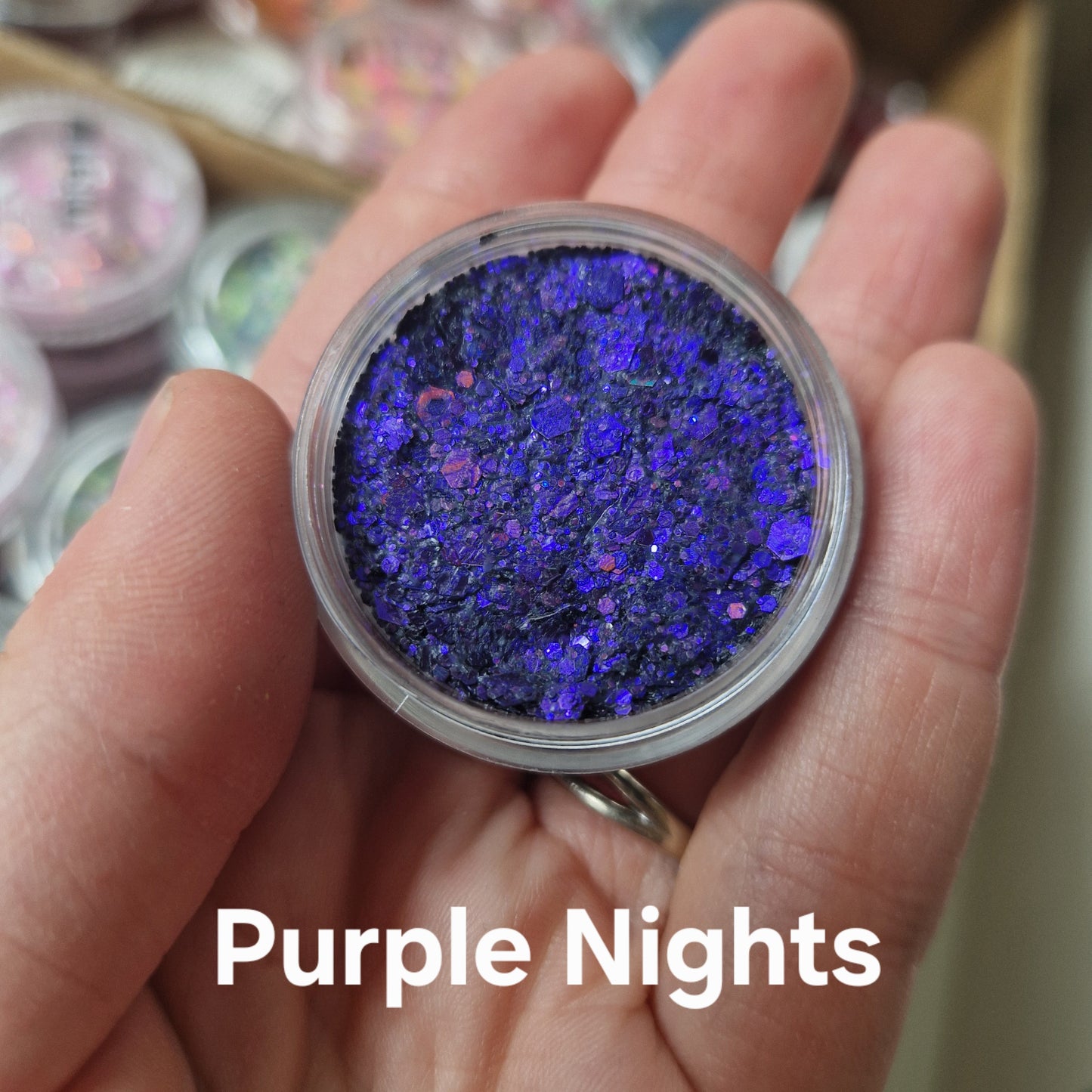 Purple Nights Glitter Cream - blå og lilla glitter i klar beholder holdt i hånd, show sparkle effekt