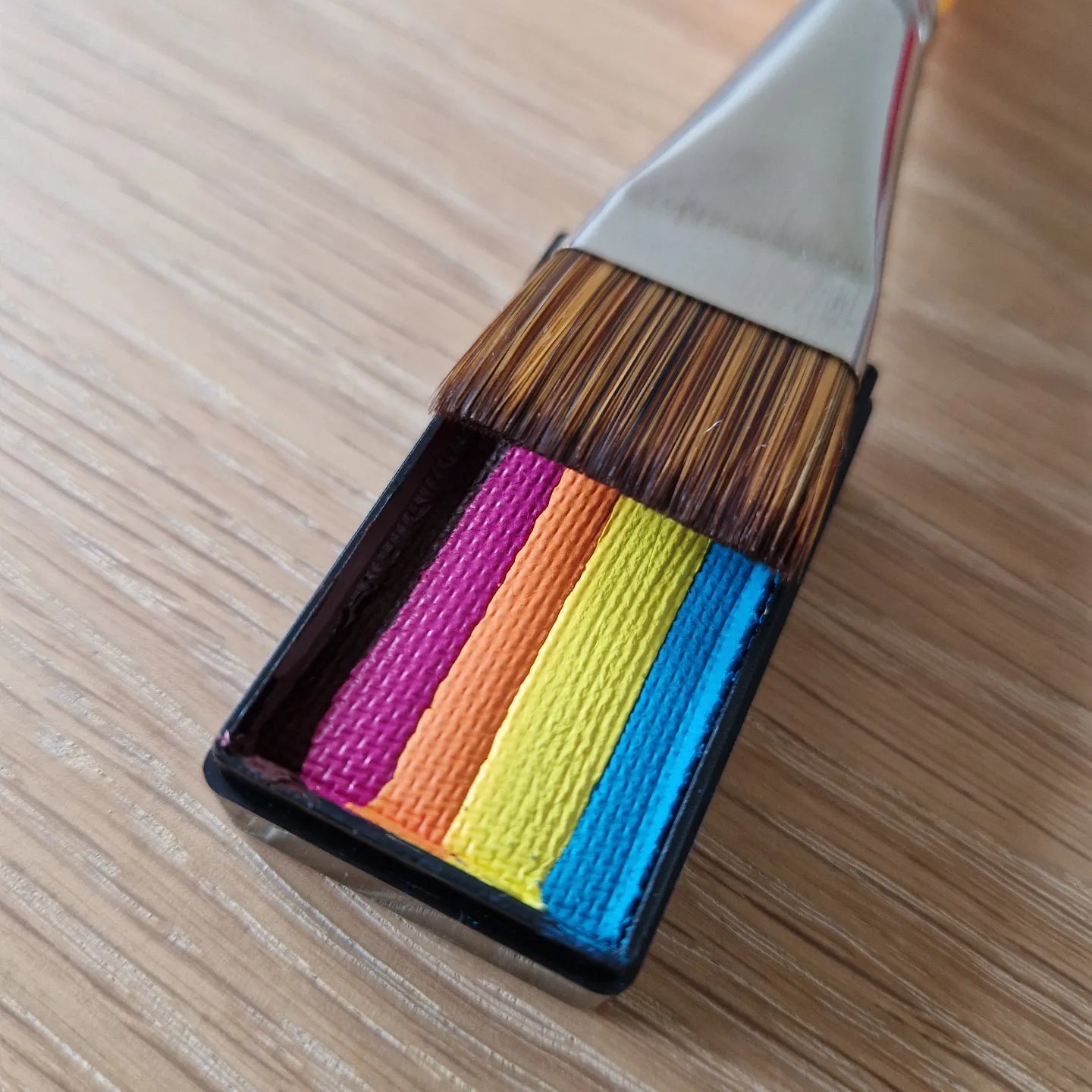 1 inch Firm Stroke pensel med firkantede hår og regnbuefarvede split cake farver på træbord